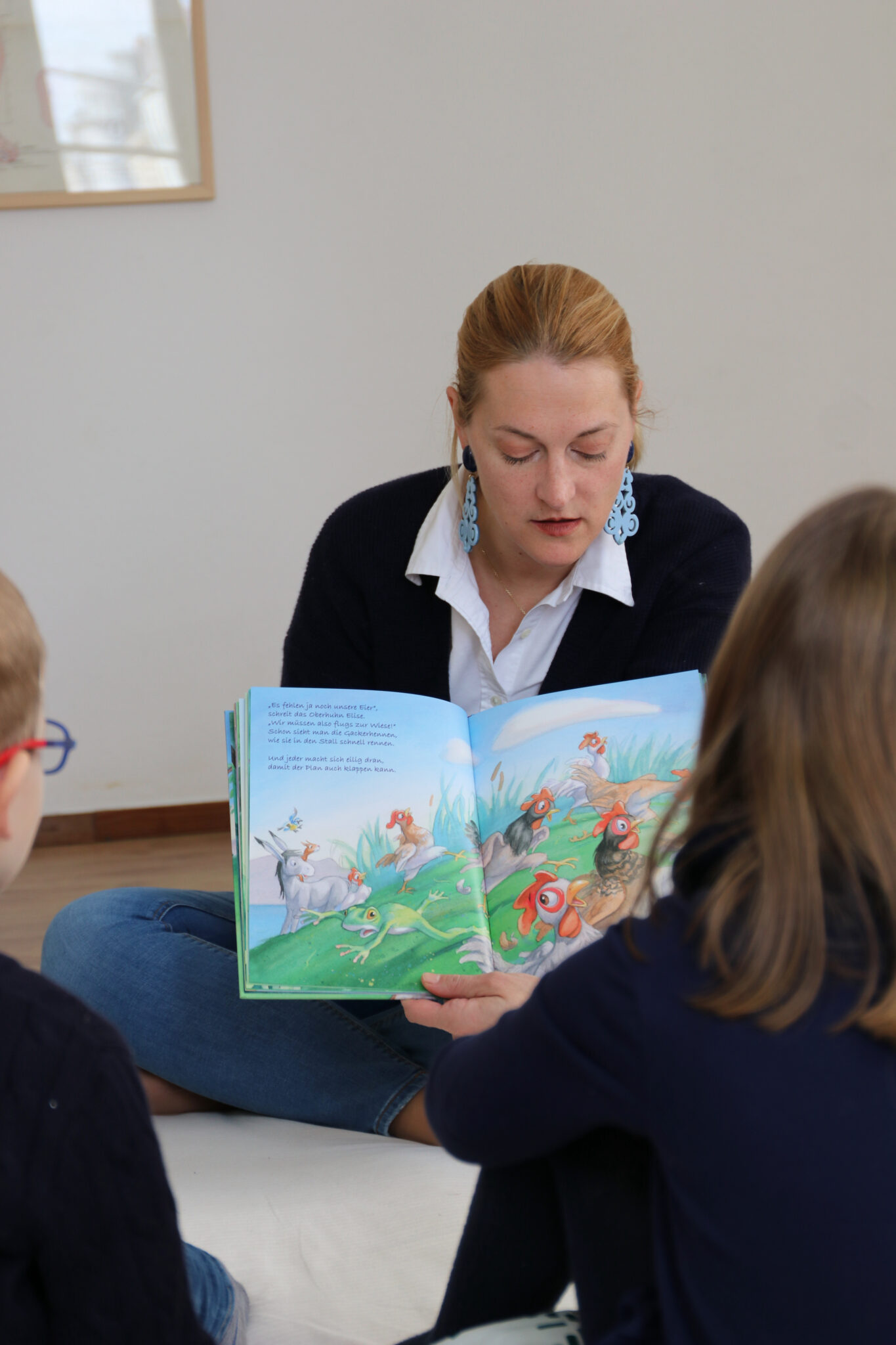 Julia zeigt den Kindern das Kinderbuch, während sie weiter vorliest.