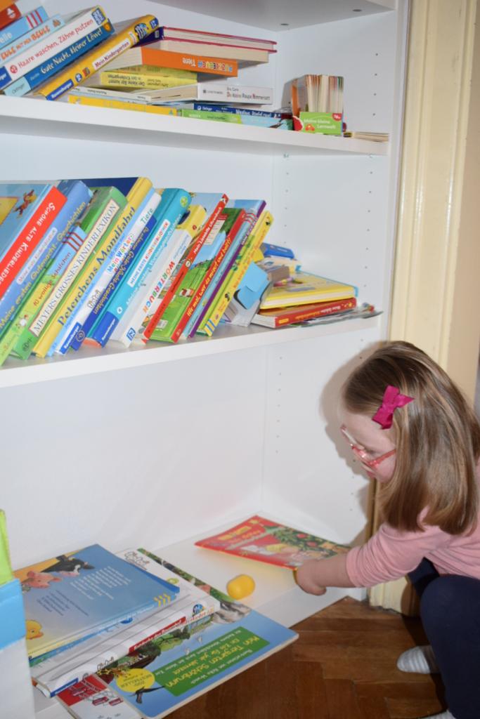 Kind bei der Bücherauswahl für die Lesewerkstatt, individuelle Spielgruppe für Sprachkompetenz